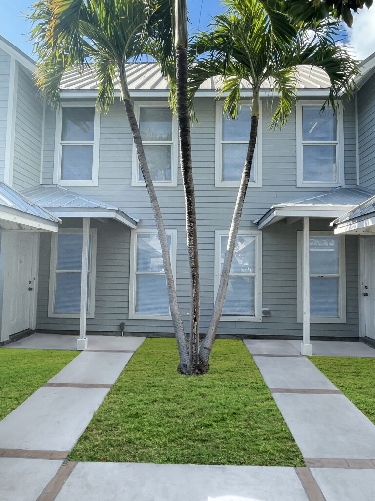 Lawn of a white house with palm trees