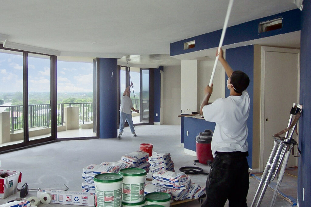Two workers painting the ceiling
