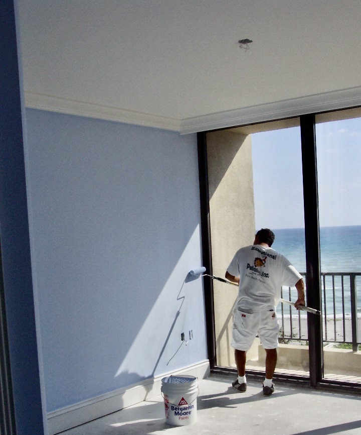 Worker painting the wall with blue paint