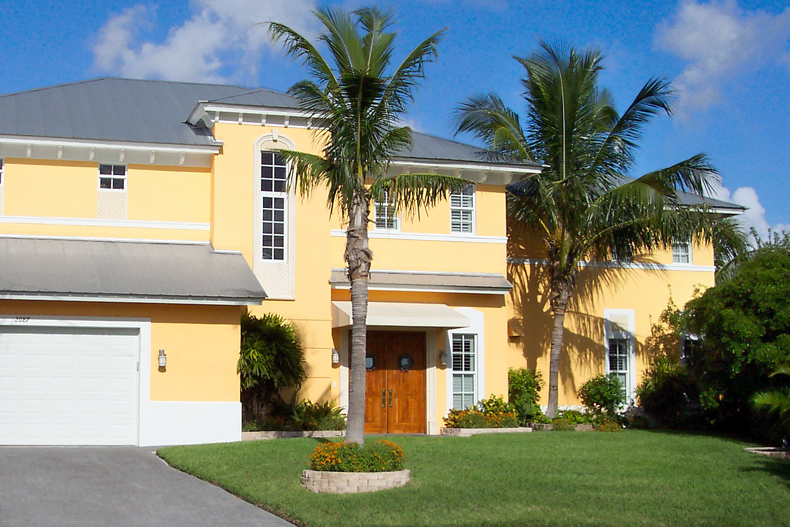 Font lawn of a two storey house with two coconut trees