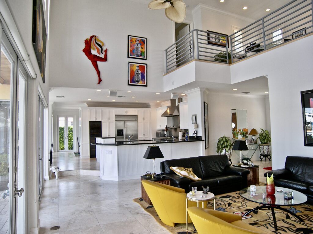 House interior with white walls, black sofas and kitchen
