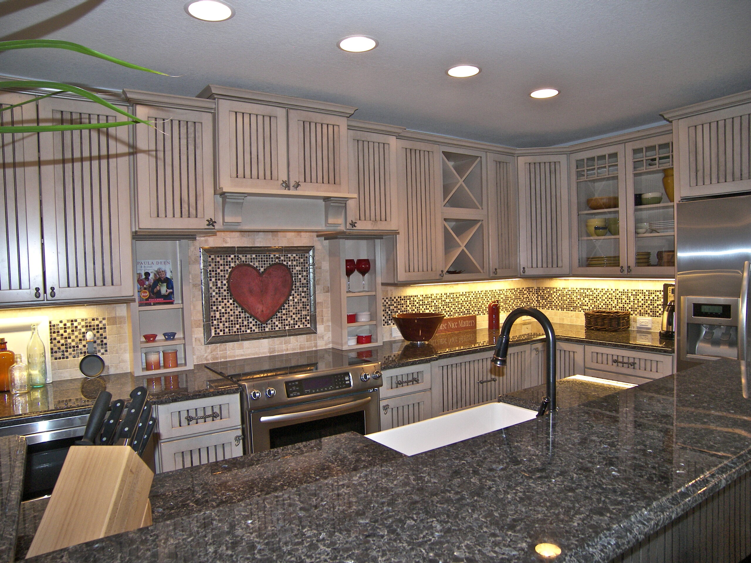 Sink and kitchen area of with a heart tile wall