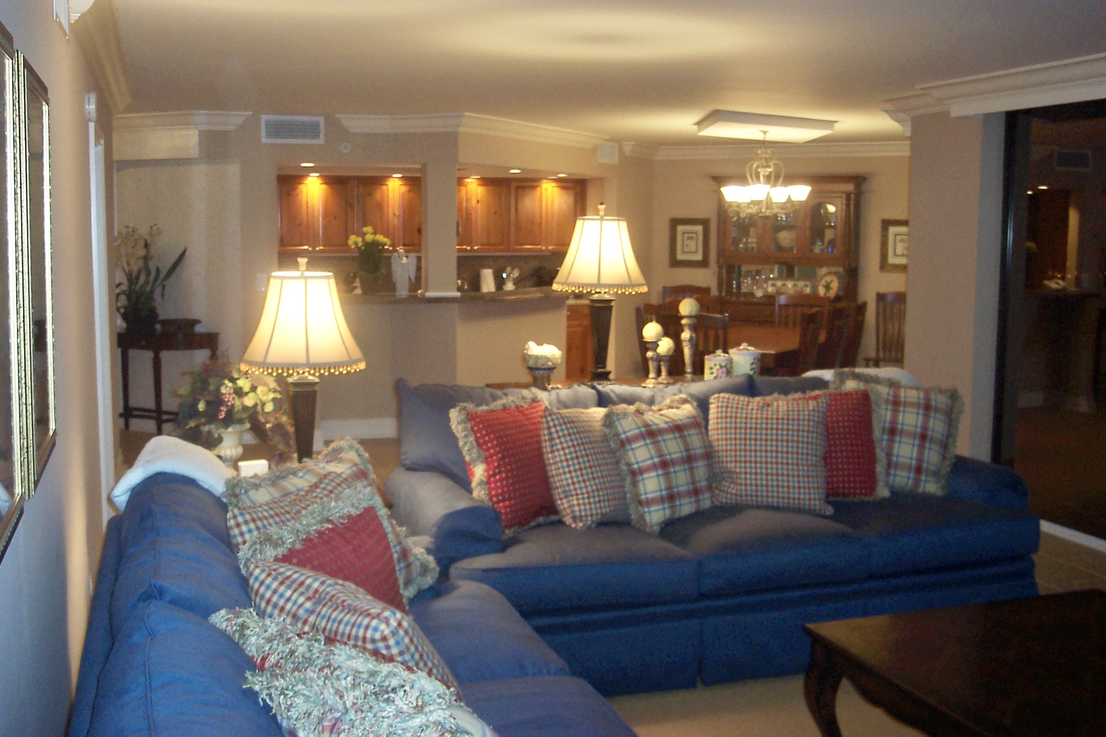 A photo of a house with blue sofas standing lamps and glimpse of the dinning and kitchen area